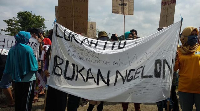Warga Adimulyo membentangkan spanduk saat aksi unjukrasa. (Foto: Istimewa)
